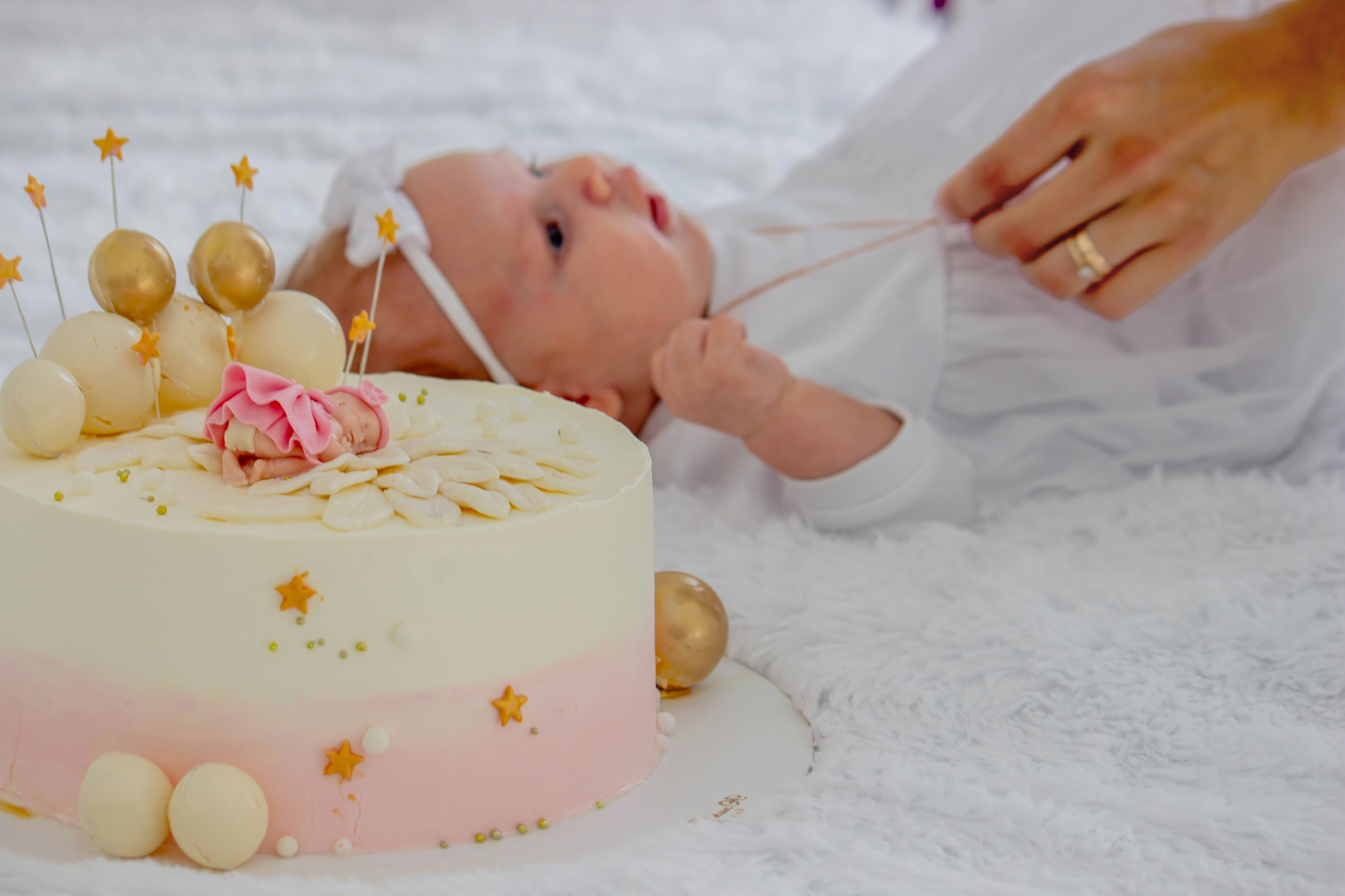 Naming day celebration — a baby in white beside a beautifully decorated christening cake