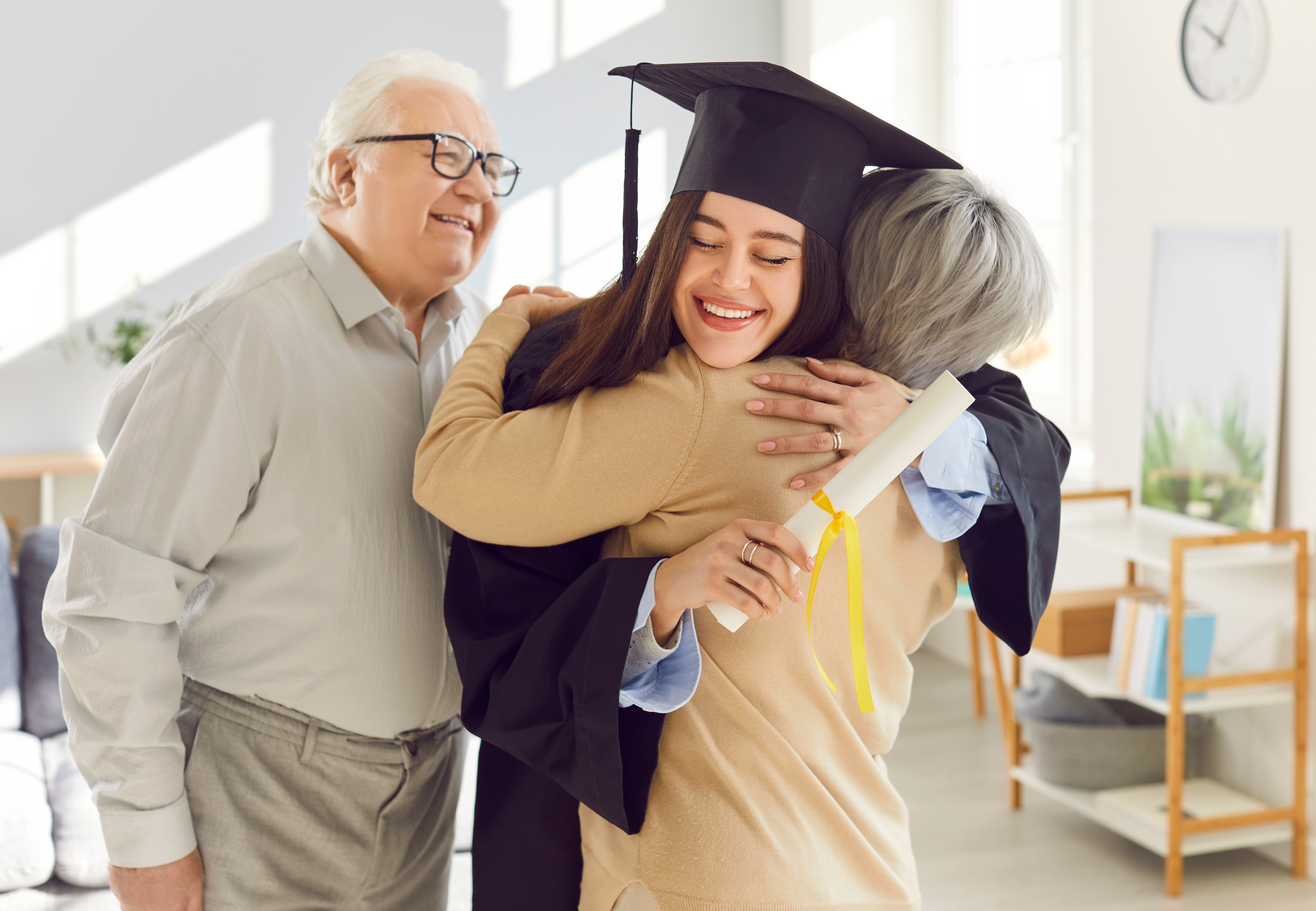 Graduation ceremony celebrant — a graduate in cap and gown embracing family members